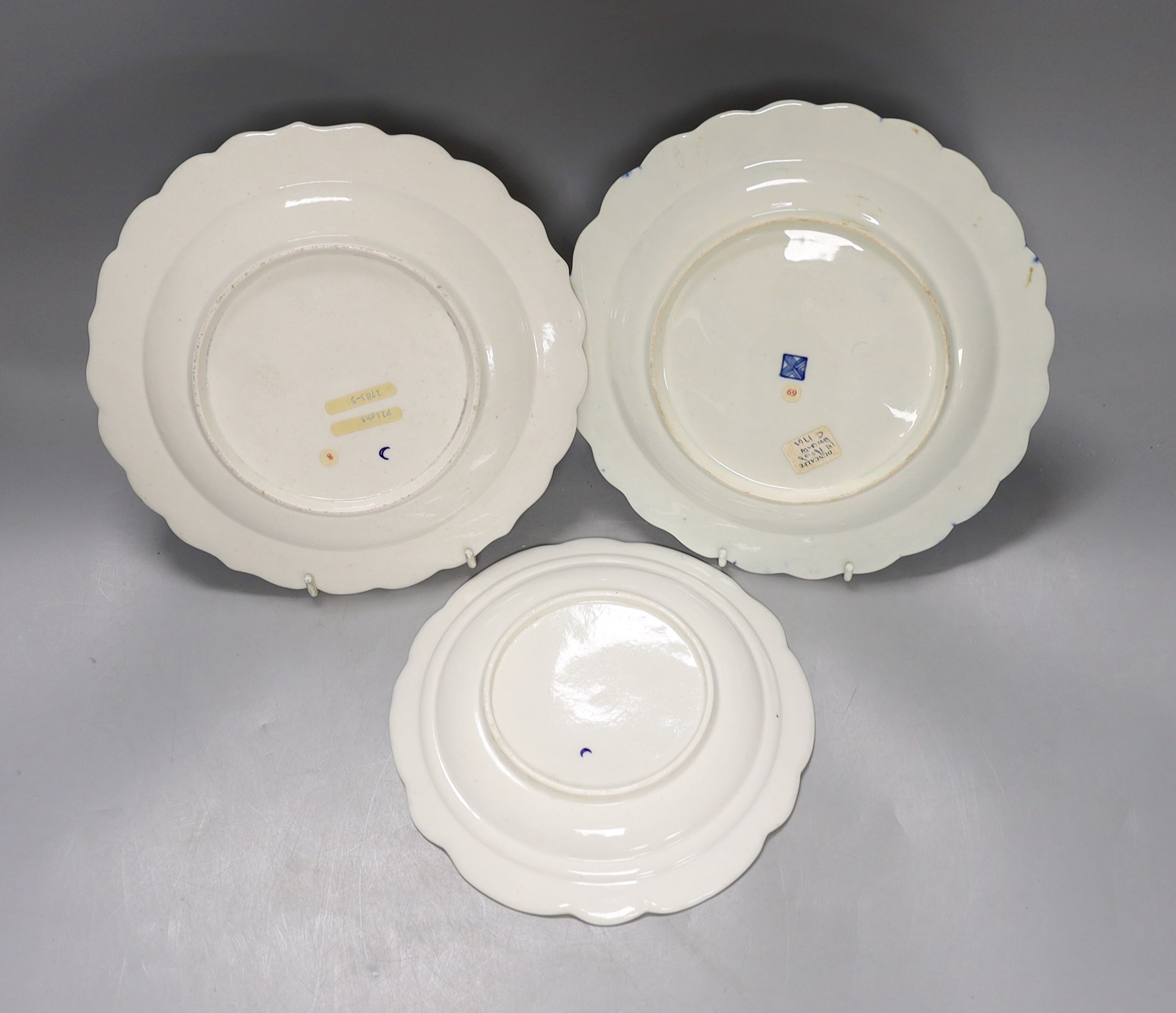 Three Worcester plates having blue border, one with elaborated gilding enclosing a bouquet of flowers, two plates both with a star shaped foliate design in the centre, c.1775, largest 21.5 cm